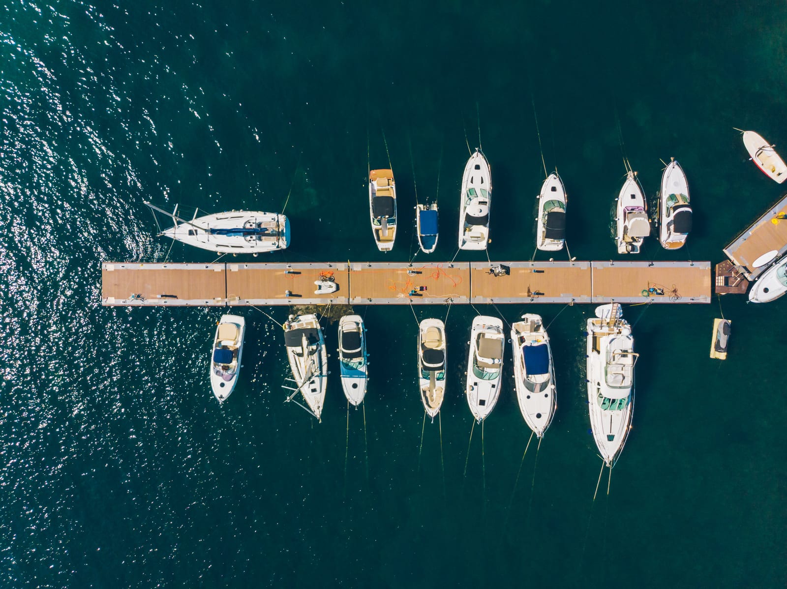 Aerial view looking straight down on a marina dock with powerboats and sailboats moored along both sides