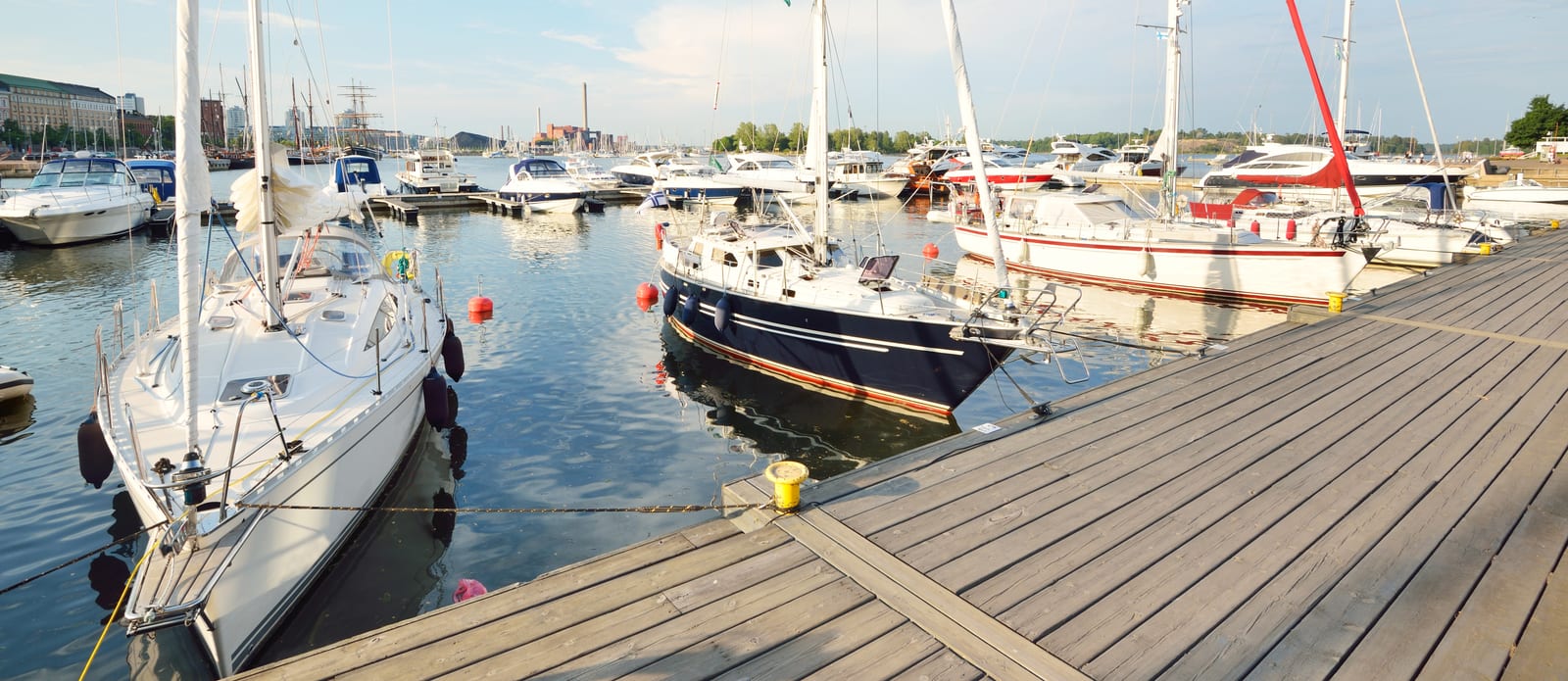 Sailboats moored alongside a timber-decked marina dock