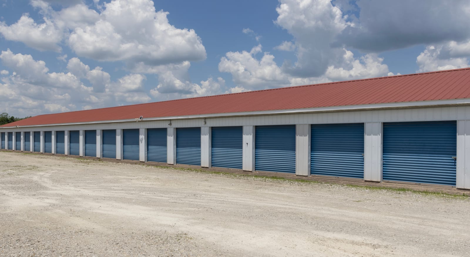 A long row of exterior drive-up self-storage units with roll-up doors